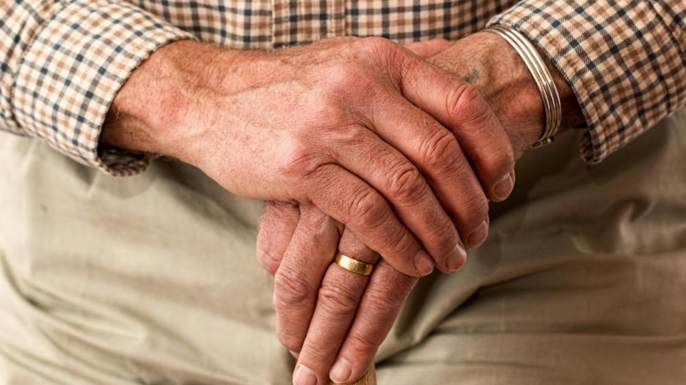 Ingezoomde foto van de handen van een oudere man die een stok vasthoudt